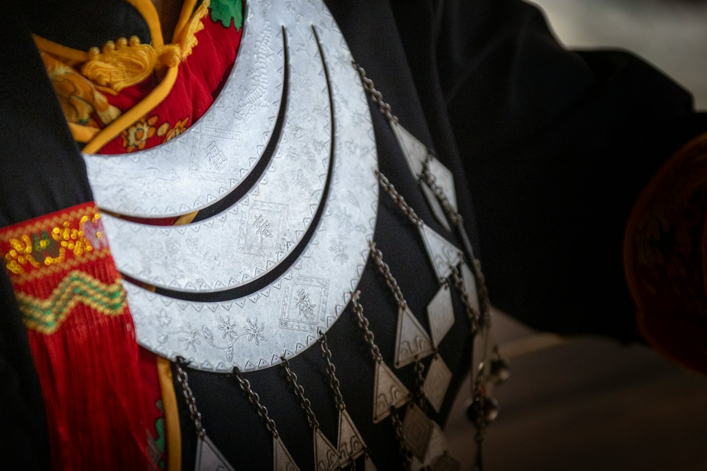 Ornate silver collar piece worn over traditional embroidered red clothing.